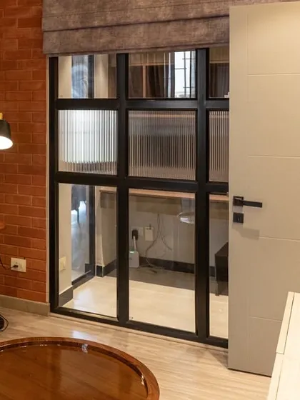 This TV lounge features an exposed brick wall, giving it a casual and industrial-chic vibe. To maintain flexibility, we installed a sliding aluminum and glass partition, which can separate the study nook without blocking light.