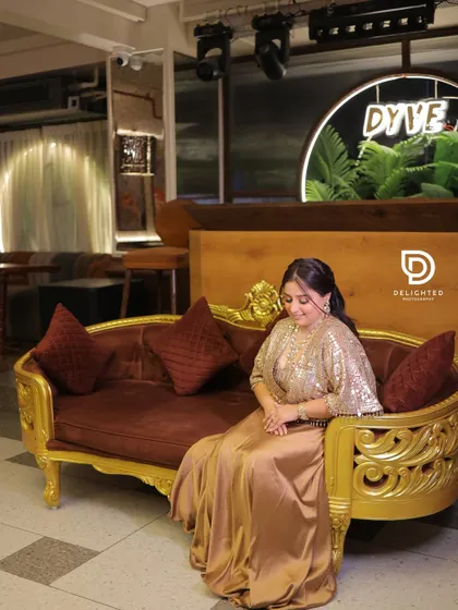 A lovely solo portrait of the bride-to-be at her Roka ceremony, seated on an ornate sofa, showcasing her elegant satin and sequin gown.