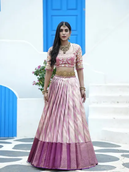 A full-length view of the pink and gold half saree, perfect for a bride or bridesmaid. The pleated skirt and embroidered blouse create a look of timeless beauty.