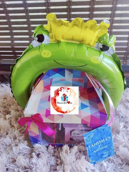 A creative return gift hamper for a kid's birthday, topped with a crowned frog prince balloon. I can create unique and fun favors in bulk for children's parties, making them a hit with young guests.