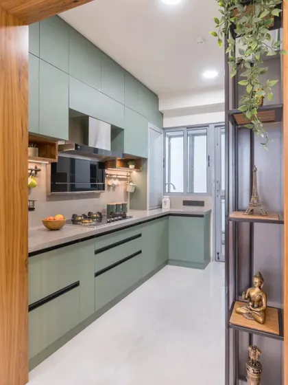 An entryway view into the sage green kitchen, framed by wood, showcasing the clean and organized parallel layout.