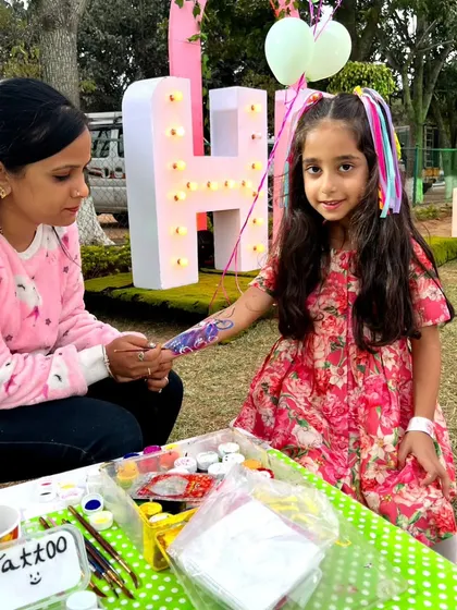 An interactive tattoo painting station at the butterfly party. A young guest is getting a colorful butterfly painted on her arm, a popular activity for all the kids.