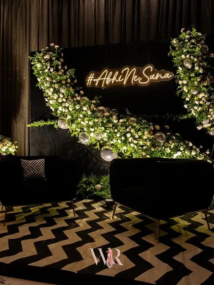 This photo booth for the Jazz Club-themed night featured a custom neon sign with the couple's hashtag, #AbhiNeSuna. The backdrop of white florals and disco balls against a black wall provided a chic and fun spot for guest photos.