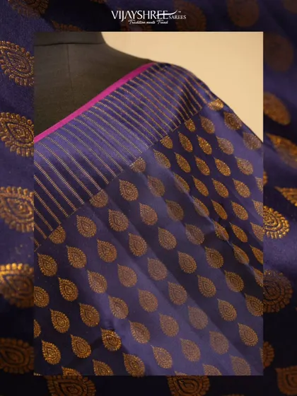 A close-up of the shimmering gold leaf buttas against the deep blue silk.
