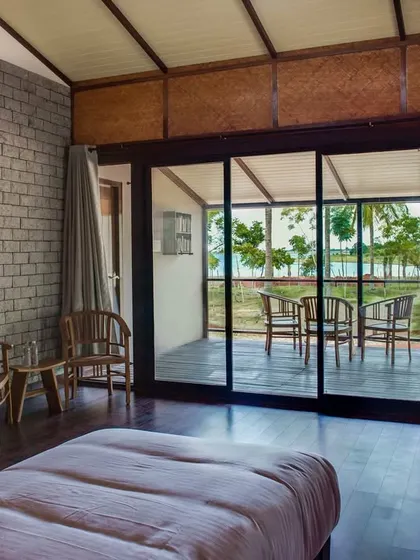 The bedroom of the Pool Villa, with large sliding glass doors that offer direct access to the deck and views of the river.