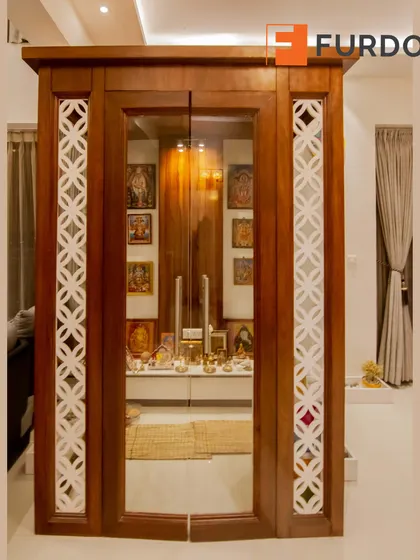 We designed this dedicated pooja room with traditional elements, including ornate white jali work on a wooden frame and glass doors to create a serene and sacred space.