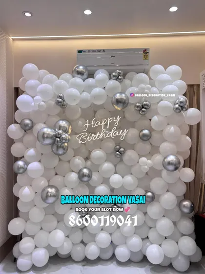 A clean and modern birthday balloon wall made entirely of white and silver balloons. The "Happy Birthday" sign is placed directly on the balloons for a floating effect.