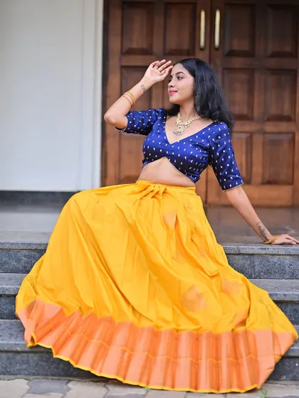 A full-length shot showcasing the bright yellow and blue lehenga. The makeup is kept balanced to not overpower the vibrant colors of the outfit.
