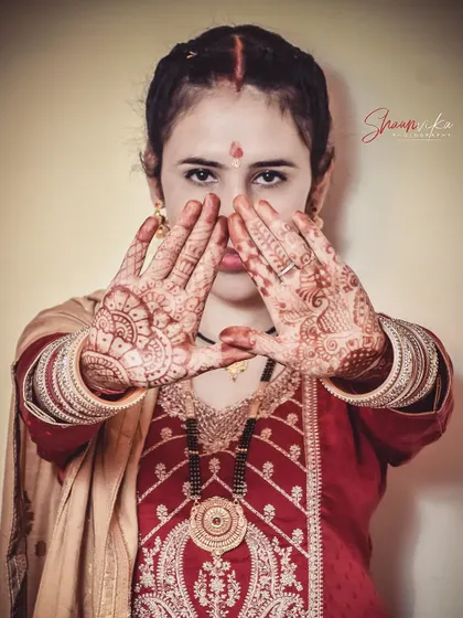 A powerful portrait of a bride in her traditional Himachali post-wedding attire, her mehndi-covered hands creating a striking frame.