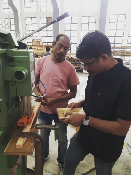 An instructor provides one-on-one guidance on the chain mortiser, helping a student perfect their technique for creating strong and accurate joints.