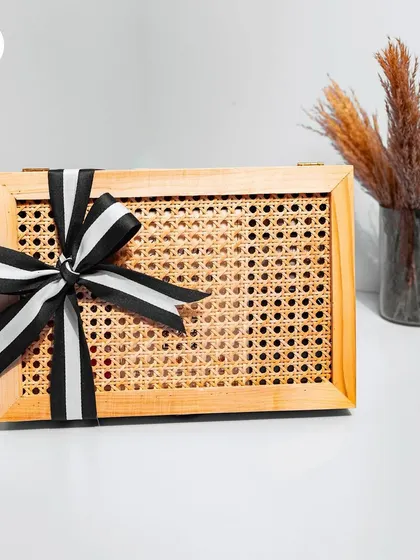 This custom box features a modern design with a cane webbing lid and a solid wood frame. Finished with a bold black-and-white striped ribbon, it's a perfect example of a sophisticated and stylish hamper for a groomsman or as a contemporary wedding gift.