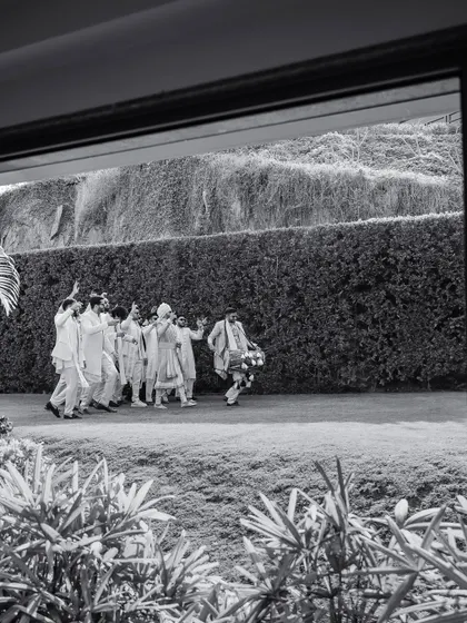 A black and white shot of a baraat procession. For 7 years, we've believed in instinct and heart, pouring our soul into every detail, from the grandest procession to the smallest gesture.