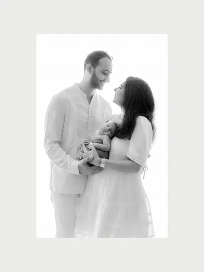 Love at first sight. A classic black and white portrait of a new family, their faces filled with joy and wonder as they hold their newborn. This is a timeless newborn photography moment.