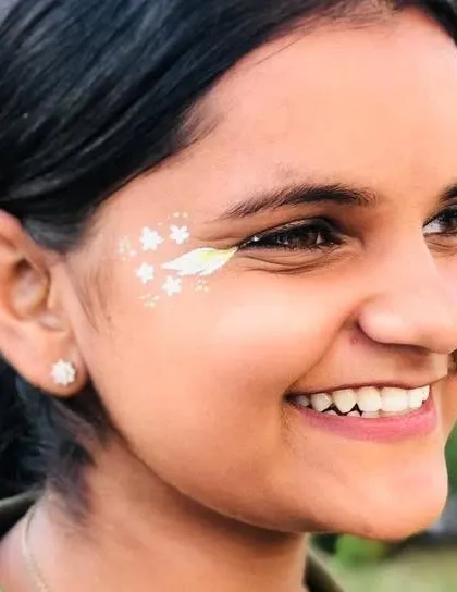A smiling client with a simple and elegant white floral design accenting her eye.