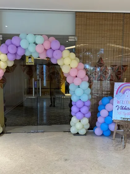 A welcoming pastel rainbow balloon arch at the entrance of a fifth birthday party, setting a cheerful tone for the celebration.