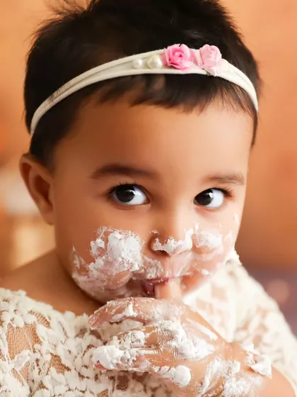 A direct, heart-melting look from the birthday girl, with frosting on her face and hands.