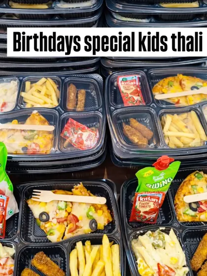 Our birthday snack trays are stacked for a bulk order, with pasta, sandwiches, fries and drink pouches visible.