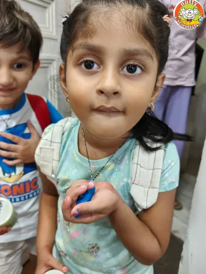 A young scientist shows off the dino tooth she painted. This activity lets kids be creative while making a cool piece of prehistoric jewelry to take home.