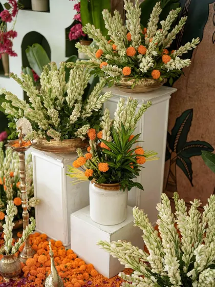 An arrangement of fresh tuberoses and marigolds in brass and ceramic pots, creating a vibrant and fragrant corner.