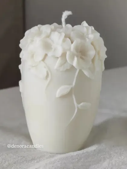 A taller, vase-shaped floral pillar candle with intricate flowers and vines.