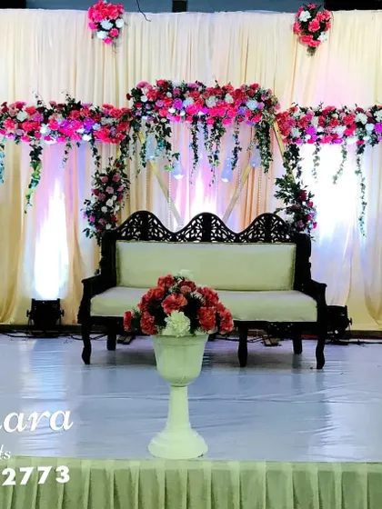A minimalist and modern stage design. This setup uses geometric hexagonal frames adorned with pink and red flowers against a simple cream backdrop, perfect for a chic and contemporary event.