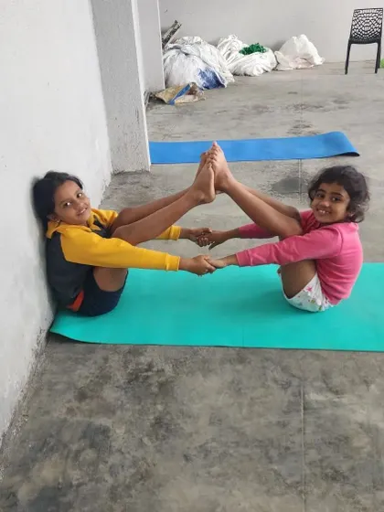 Two of our younger campers master the partner boat pose with smiles, showing that fitness is fun at any age.