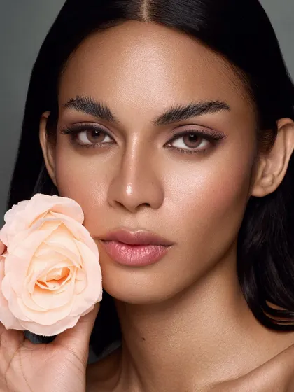 A simple, elegant portrait with a single peach rose. The color of the rose complements the model's skin tone and the warm, neutral makeup, creating a harmonious and beautiful composition.