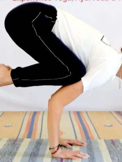 A student demonstrates strong form in Bakasana (Crow Pose). This arm balance requires a combination of strength, balance, and concentration, all of which are cultivated progressively in our classes.