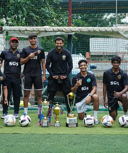 Our coaches kneeling with the team's trophies, celebrating the success that their guidance helped achieve.
