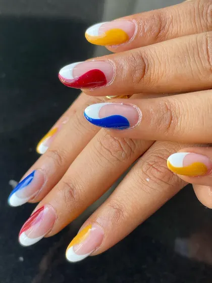 A bold and colorful abstract French manicure using primary colors: red, yellow, and blue.