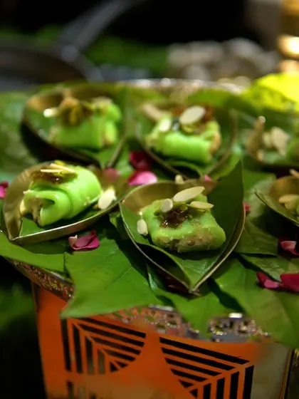 A platter of Malai Pista Beda, a traditional Indian sweet roll made with pistachio and cream, served in individual leaf cups.
