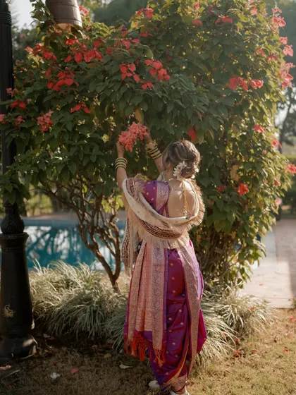 A beautiful shot from the back, showcasing the traditional nine-yard saree and the elegant floral bun, a classic hairstyle for a Maharashtrian bride.