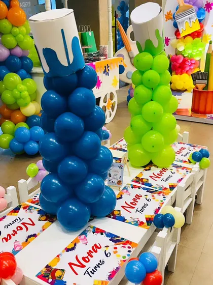 The kids' dining table is decorated with custom art-themed runners and balloon centerpieces designed to look like spilling paint buckets.