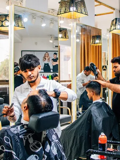 A busy day at the salon with multiple clients getting groomed. In the foreground, a client is getting a precise shave, showing the range of men's grooming services we offer.