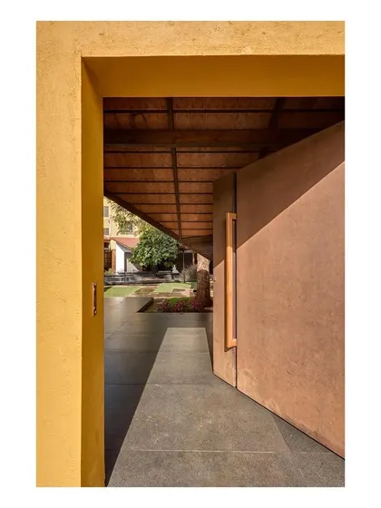 Details of the museum's exterior, where the contrast between the warm yellow walls and the corten steel doors creates a rich material palette. The design carefully balances the restoration of heritage elements with contemporary interventions.