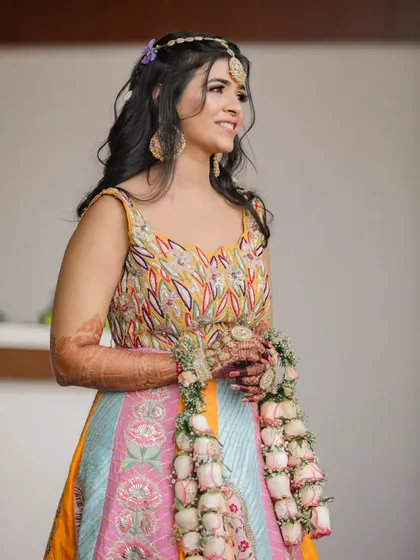 A beautiful portrait of the bride at her Haldi ceremony, wearing a colorful lehenga and delicate floral jewelry.