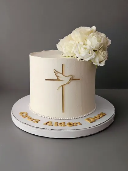 A pure and elegant cake for Cruz's First Holy Communion. This white cake is decorated with a simple cross, a dove, and fresh white roses.