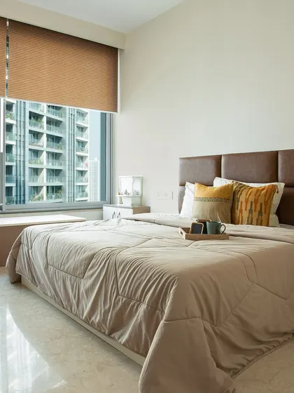 This bedroom design makes the most of a stunning city view with a large window and a cozy window seat. The warm brown headboard adds a touch of comfort.