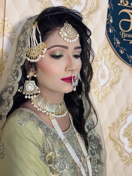A complete Muslim bridal look featuring soft green and gold cut-crease eyeshadow, bold red lips, and perfectly placed traditional jewelry. I teach my students how to create these flawless, long-lasting bridal transformations.