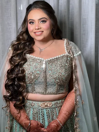 A happy bride with her Sangeet hairstyle. The soft, voluminous waves are parted to the side for a glamorous effect.