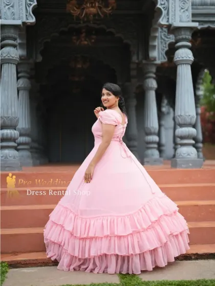 A view of the back of the pink ball gown, showing the corset-style lace-up detail and the cascading ruffles.