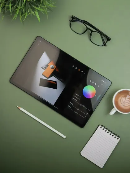 An overhead shot of the realme Pad 2, set up as a creative's workspace. This image shows the tablet being used for editing, surrounded by coffee and glasses, highlighting its utility for professionals.