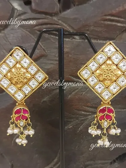 These Dakshinaya earrings showcase traditional South Indian design with a modern twist. The diamond-shaped stud features a floral motif and a ruby-colored drop, perfect for a classic, ethnic look.