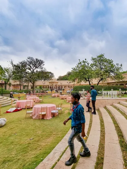 A behind-the-scenes look at my team setting up for an outdoor event at Udaivilas. Even in the midst of preparation, the beauty of the palace grounds under a cloudy sky is undeniable.