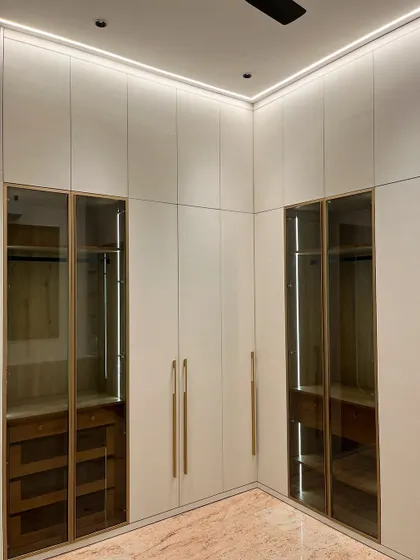 This floor-to-ceiling wardrobe in an Ambala master bedroom combines closed storage with glass-fronted sections. The integrated lighting inside the glass units allows for displaying accessories while keeping them organized.