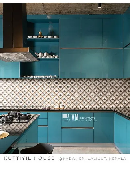 The kitchen at Kuttiyil House is a statement in color and pattern, with its vibrant teal cabinets, geometric backsplash, and a breakfast counter integrated into the island.