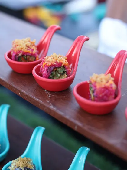 A vibrant display of our appetisers. We present our colourful sushi creations in individual spoons, arranged beautifully on wooden boards for a rustic yet elegant presentation.