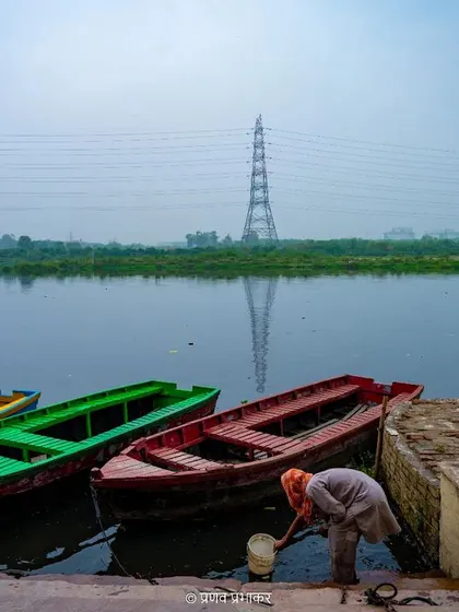 A slice of life at Yamuna Ghat in Delhi. This photograph captures an elderly man by the colorful boats, a simple, everyday scene that tells a story about the city's relationship with the river.