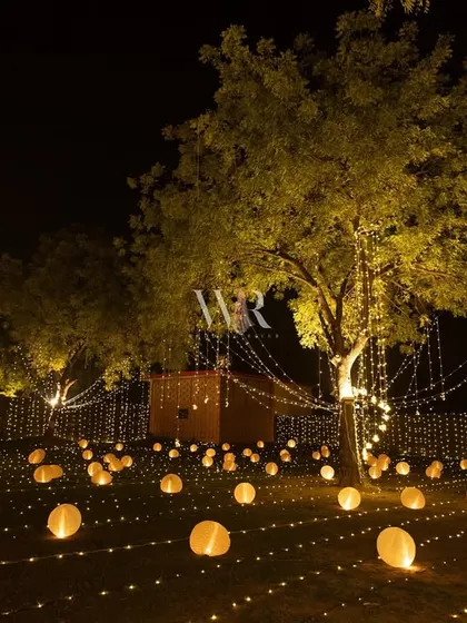 A field of glowing orbs and hanging fairy lights. This outdoor lighting design created a whimsical and immersive pathway for guests to explore.