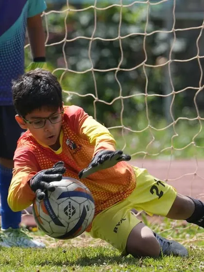 A young goalkeeper making a diving save during a friendly match on our Ooty tour.